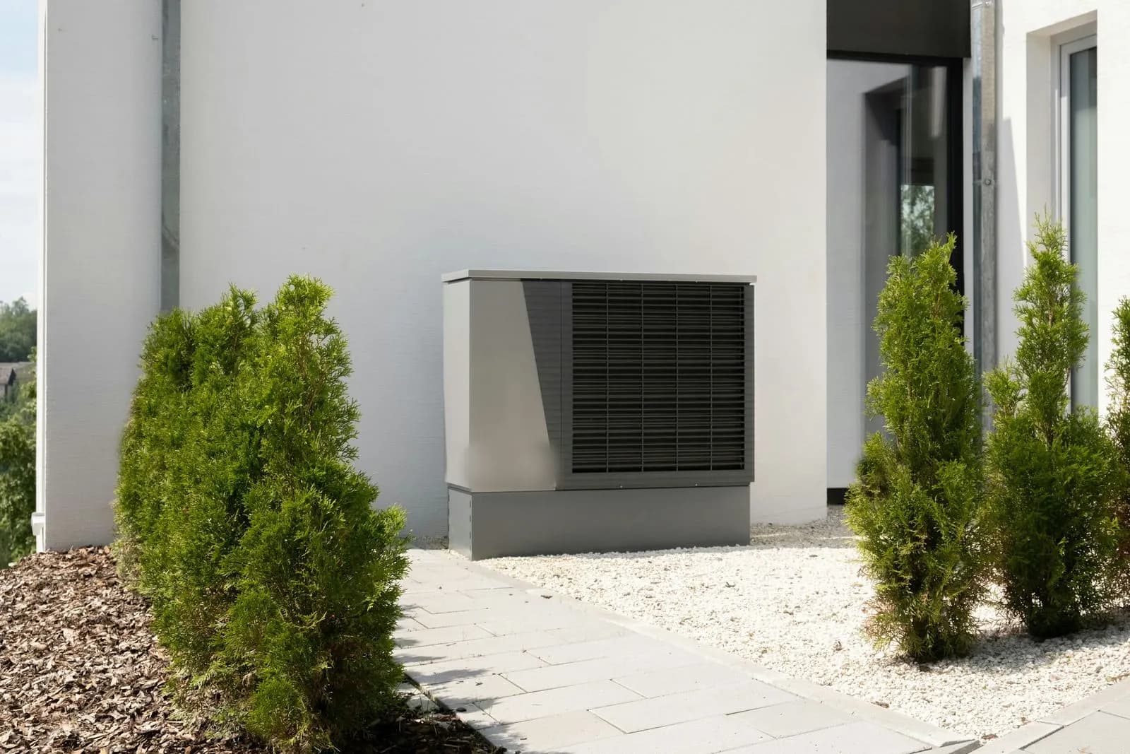 Bomba de calor aerotérmica junto a una vivienda moderna de fachada blanca