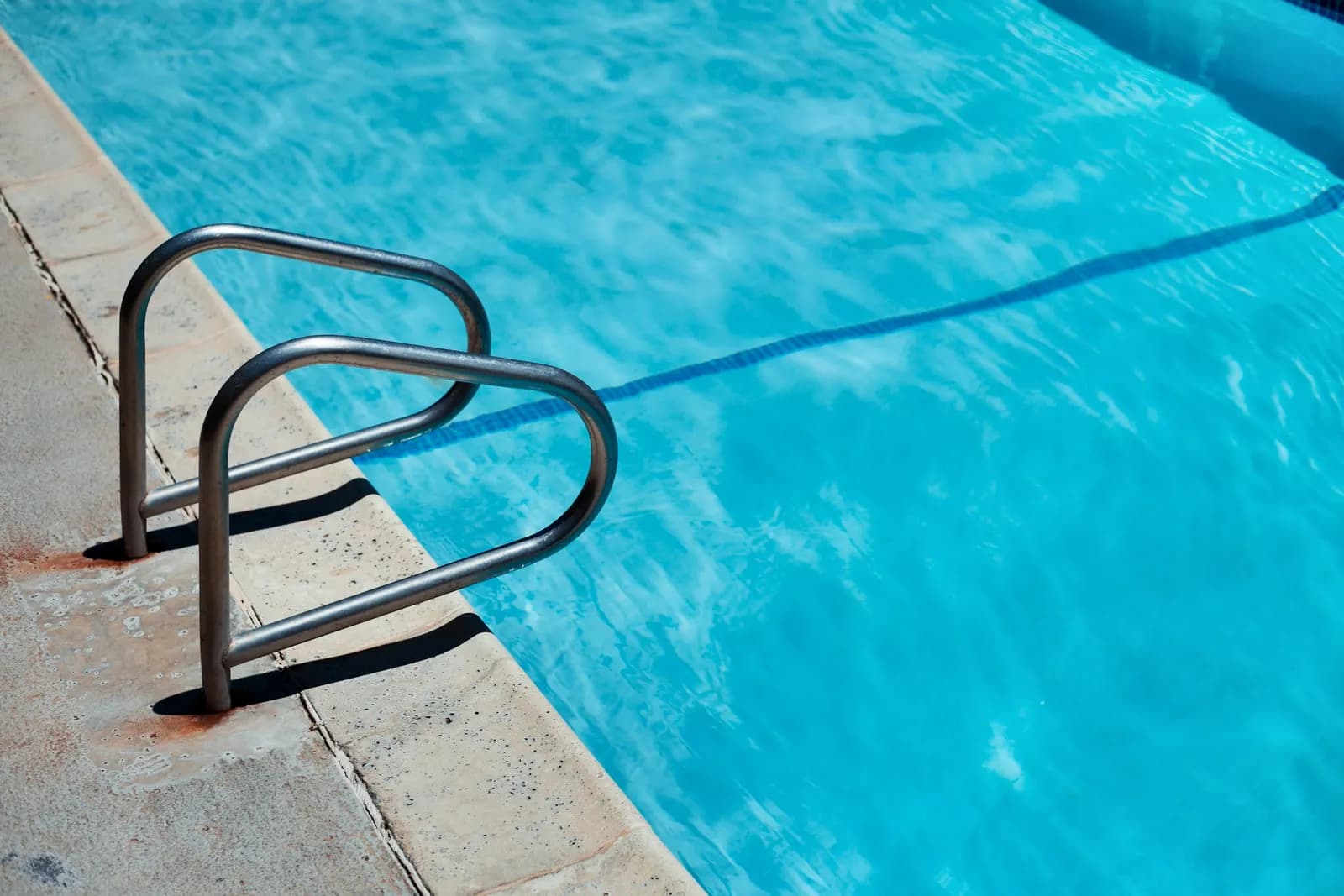 Escalera de acero de una piscina con el agua en calma