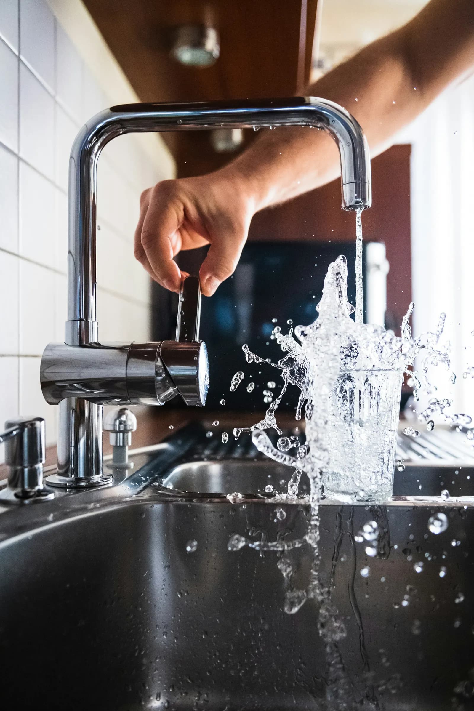 Grifo de cocina con el chorro de agua cayendo en un vaso